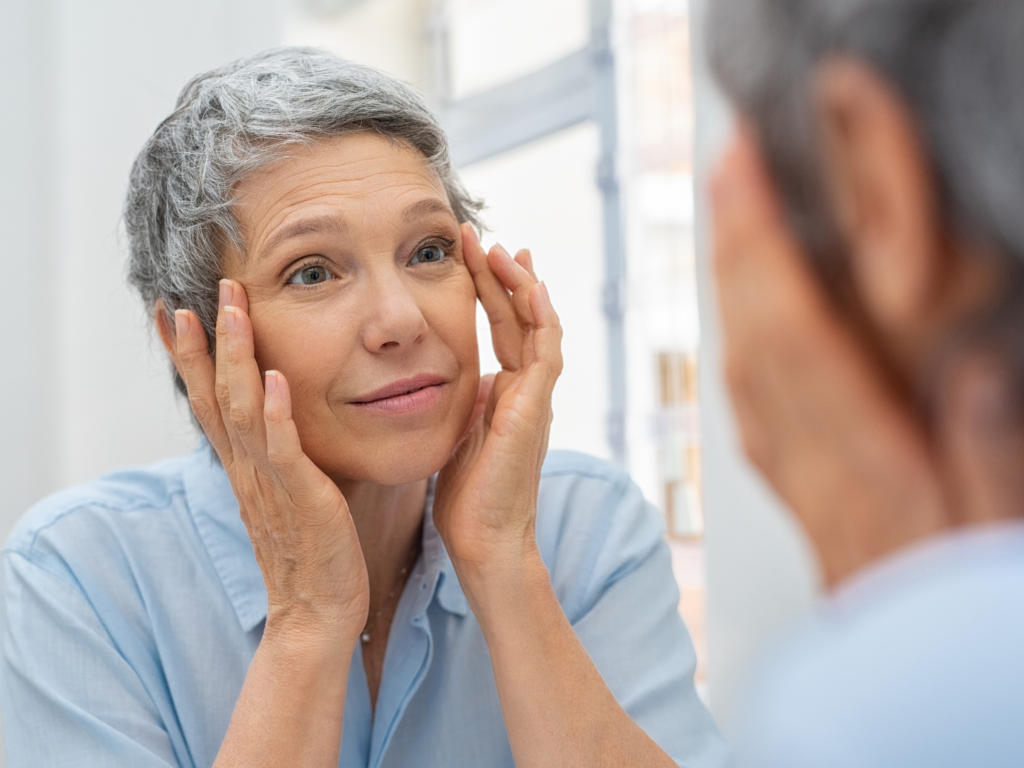 Woman looking at her reflection in the mirror with concern about facial wrinkles, featured in an article about anti-wrinkle consultations in Adelaide.
